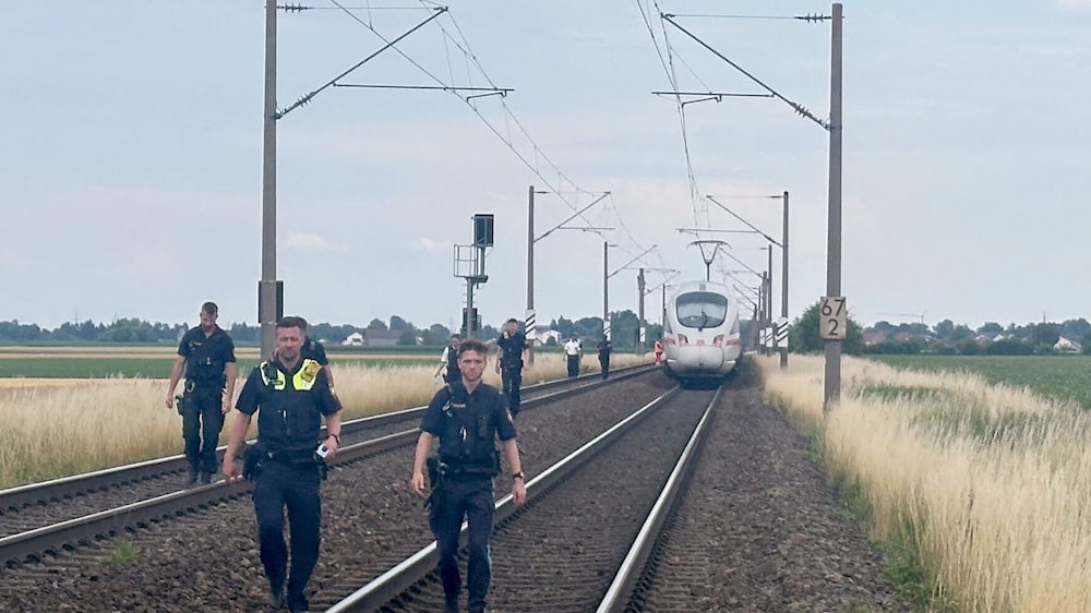 Polizisten gehen die Gleise ab.