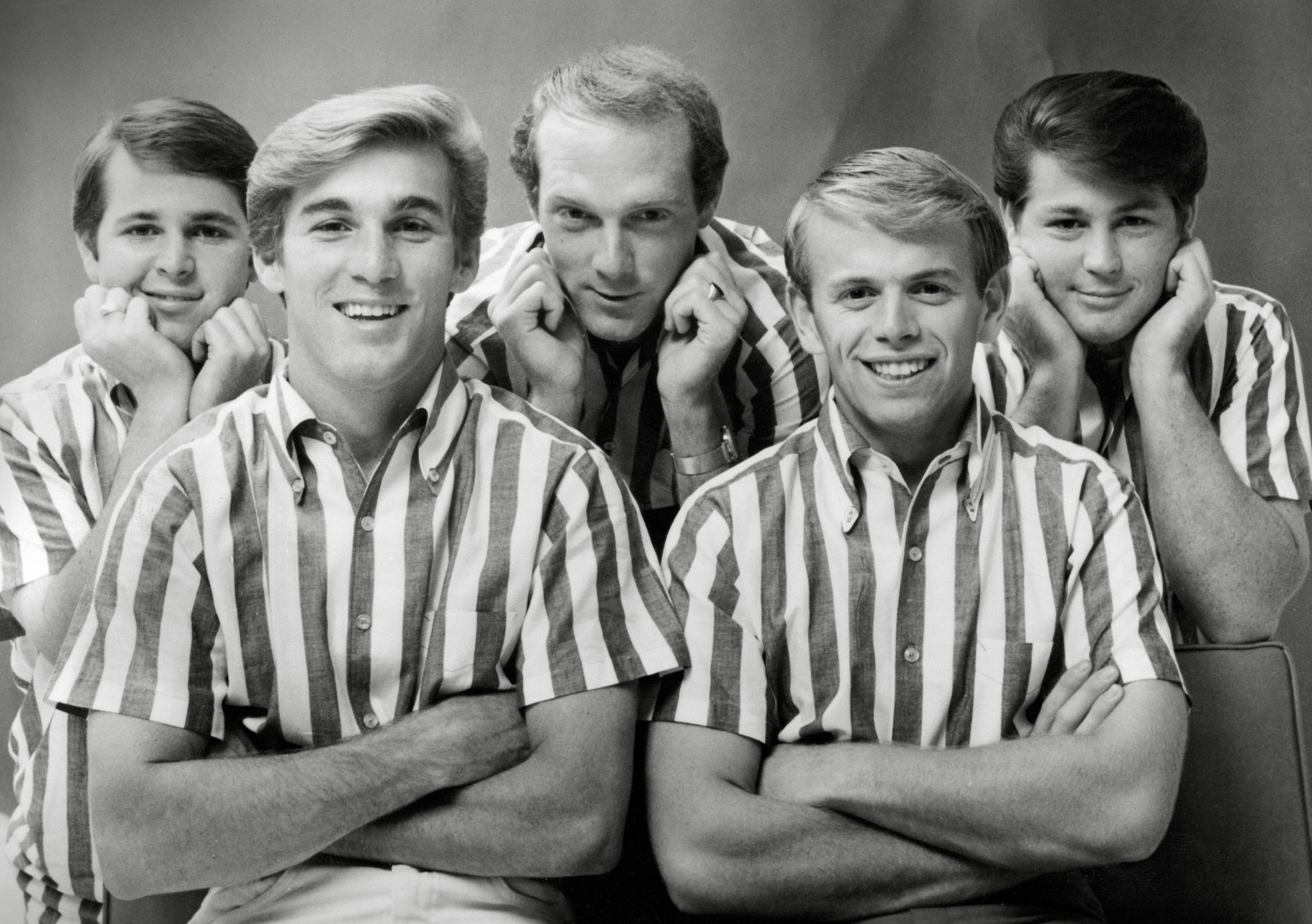 Die Beach Boys, Carl Wilson, Dennis Wilson, Mike Love, Al Jardine und Brian Wilson, circa 1962, in gestreiften Hemden vor einem Studiohintergrund.