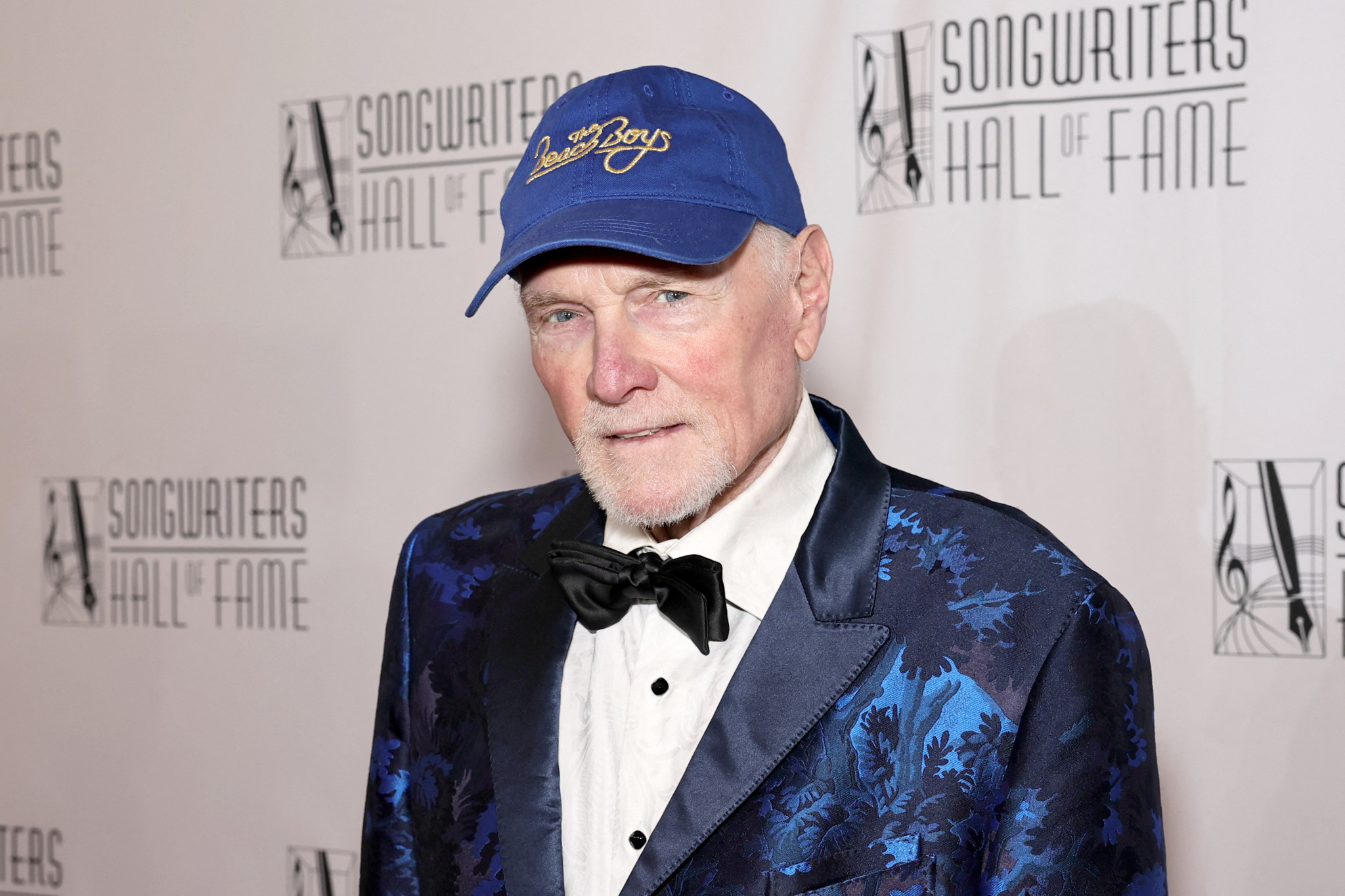 Mike Love in blauem, gemustertem Anzug und Baseballmütze bei der Songwriters Hall of Fame Einführungszeremonie 2025.