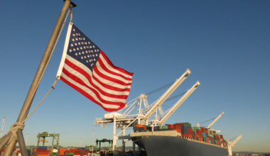 BVE zum Zollkompromiss: Hafen mit Containern liegt im Hafen; davor flattert Flagge der USA im Wind.