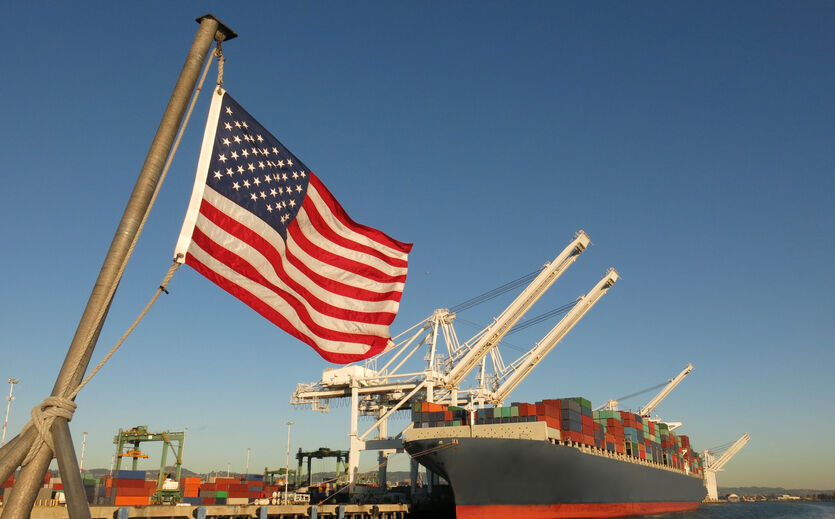 BVE zum Zollkompromiss: Hafen mit Containern liegt im Hafen; davor flattert Flagge der USA im Wind.