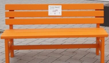Vor der Wiesbadener Lutherkirche wird eine orangefarbene Bank als Zeichen gegen Gewalt an Frauen aufgestellt.