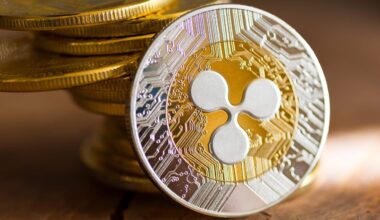 Eine Nahaufnahme einer XRP-Kryptowährungsmünze mit ihrem Logo, mit einem Stapel ähnlicher XRP-Münzen im Hintergrund auf einer Holzoberfläche.