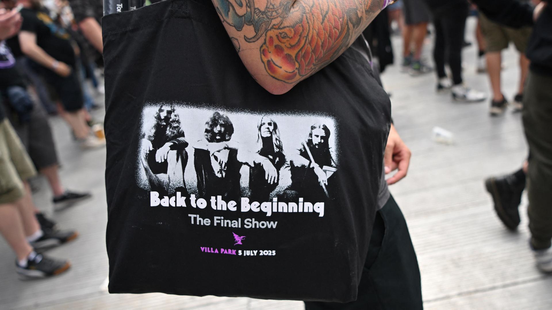 Ein Fan trägt eine Tasche mit dem Aufdruck von Black Sabbath aus der Gründungszeit und der Aufschrift "Back to the Beginning".