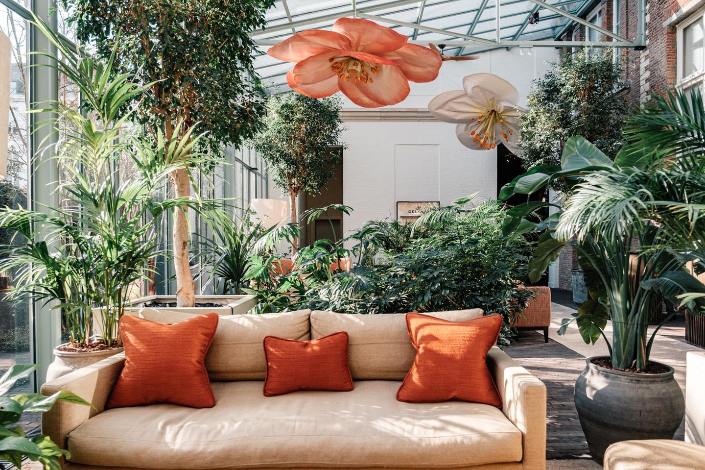 Hotel-Lobby mit beigem Sofa, Pflanzen Blumen-Skulpturen an der Decke
