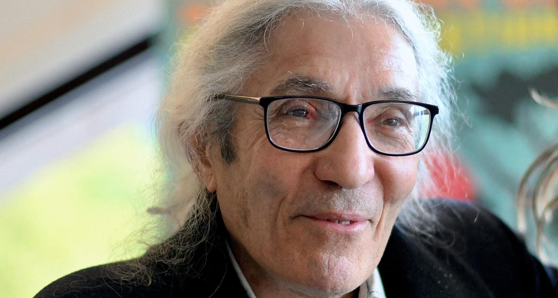 Das Bild zeigt den algerischen Schriftsteller Boualem Sansal. Er hat längere weiße Haare und trägt eine schwarze Brille.