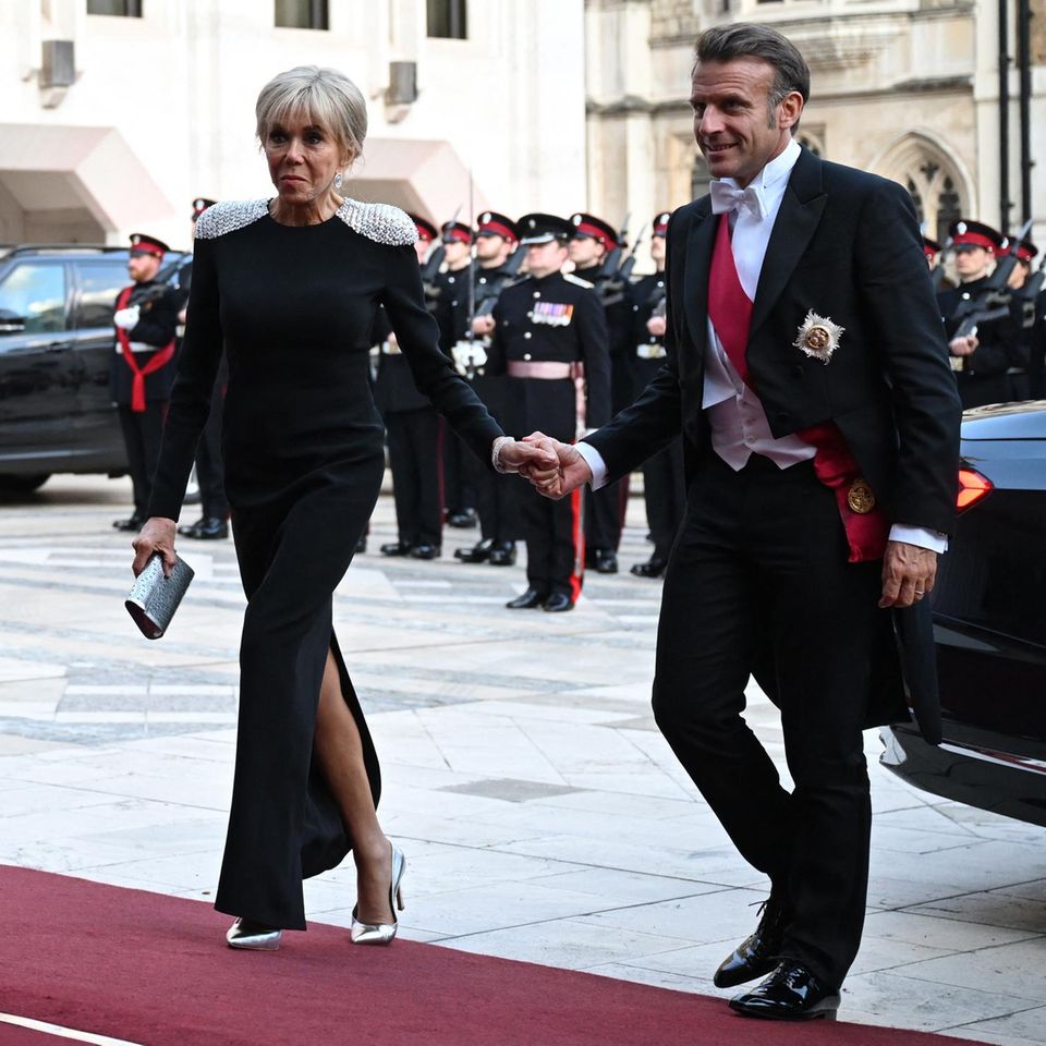 Brigitte Macron erscheint an der Seite ihres Mannes in einem schwarzen, enganliegenden Kleid mit Beinschlitz und silber-glitzernden Epauletten zum Staatsbankett. 