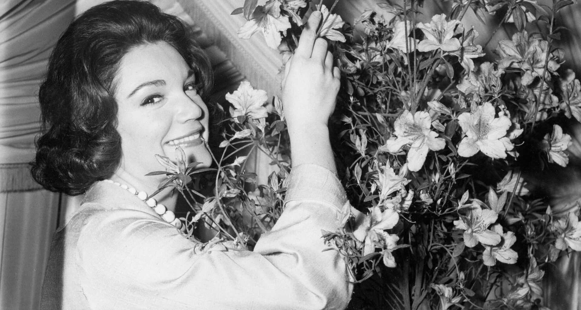 Connie Francis riecht an einem großen Blumenstrauß. Das Foto ist schwarz-weiß.