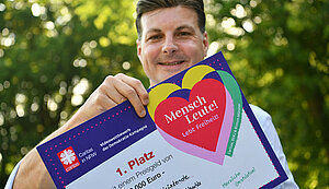 Diözesancaritasdirektor Dominique Hopfenzitz hält stolz die Urkunde für den 1. Platz in die Kamera.