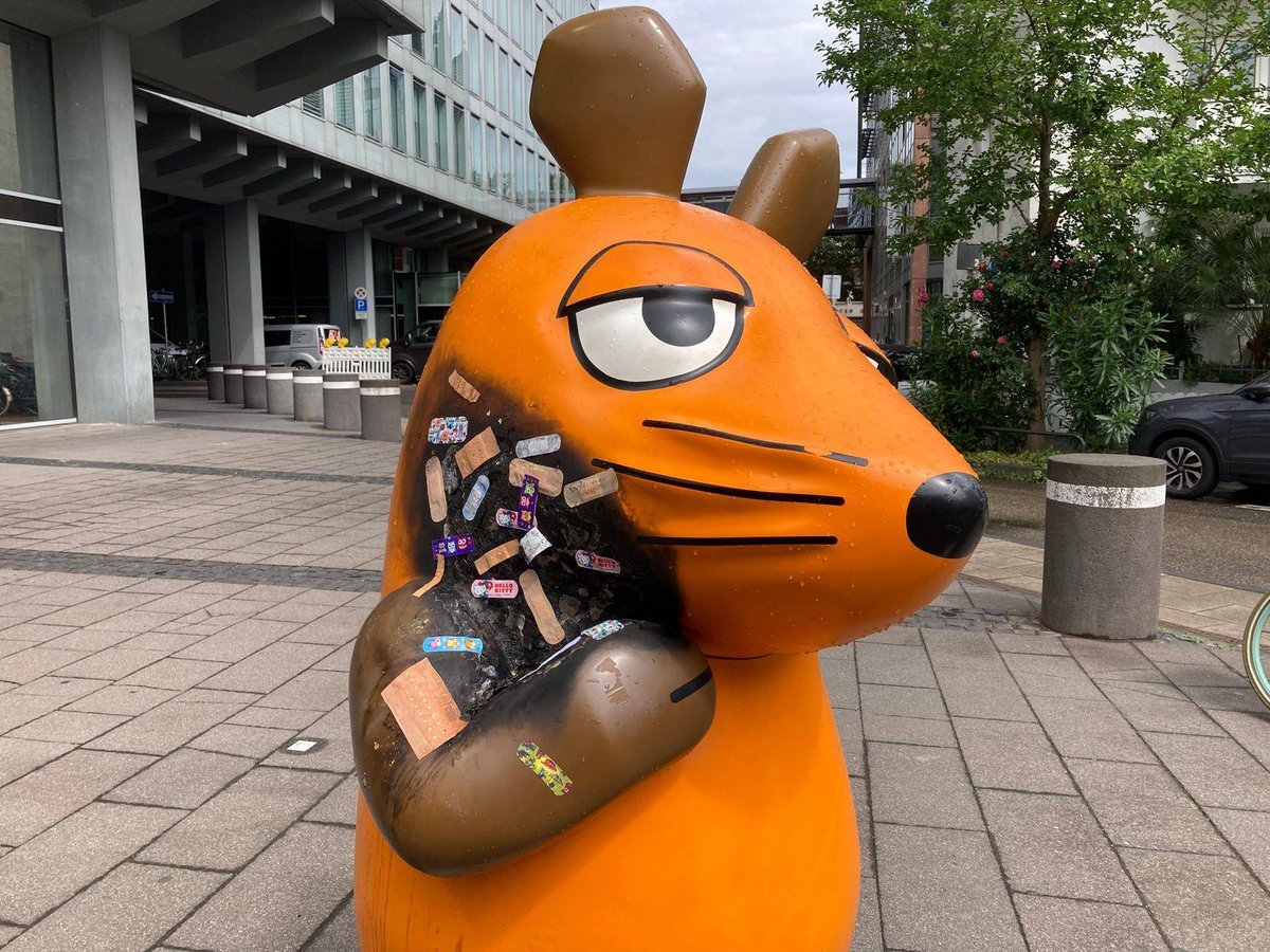 Köln | Angebrannte Maus-Figur wird mit Pflastern versorgt