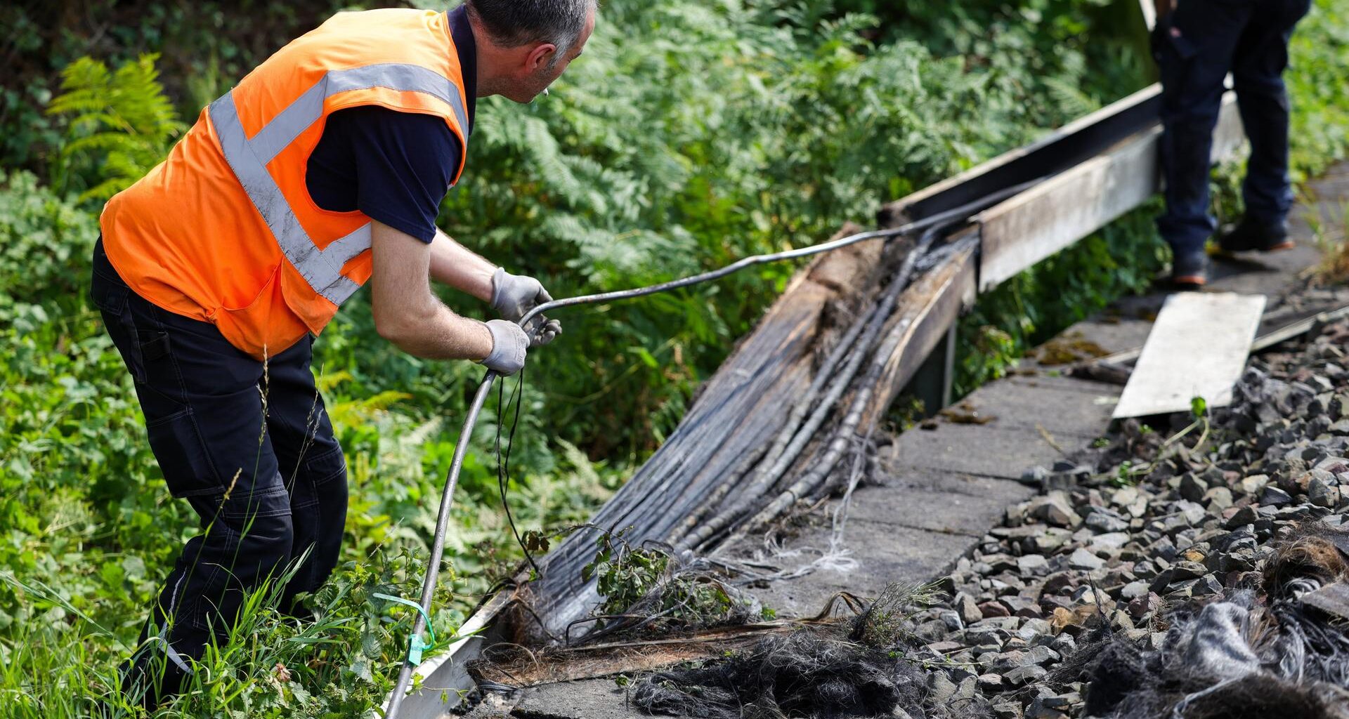 Mitarbeiter der Deutschen Bahn arbeiten an einem Gleisabschnitt in Düsseldorf. Dort wurde neben der Bahnstrecke Feuer in einem Kabeltunnel gelegt, der sechs Kabel in Mitleidenschaft zog.