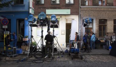 Eine Filmcrew baut ein Set mit Scheinwerfern vor einem Mehrfamilienhaus auf