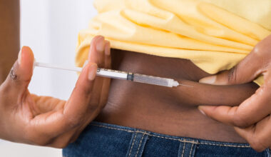 Nahaufnahme einer schwarzen Person, die sich eine Spritze in den Bauch injiziert