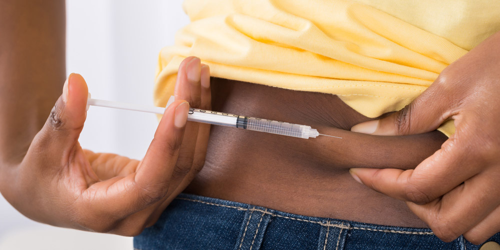 Nahaufnahme einer schwarzen Person, die sich eine Spritze in den Bauch injiziert