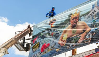 Arbeiter installieren eine Plakatwand der Künstlerin Karen Fiorito in Phoenix. Das Werk mit dem Titel „Swamp King“ kritisiert Donald Trumps Präsidentschaft mit Bildern, die Korruption, Autoritarismus und systemischen Verfall symbolisieren.