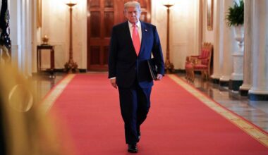 Donald Trump mit Aktenmappe unter dem Arm auf dem roten teppich in einem Korridor des Weißen Hauses