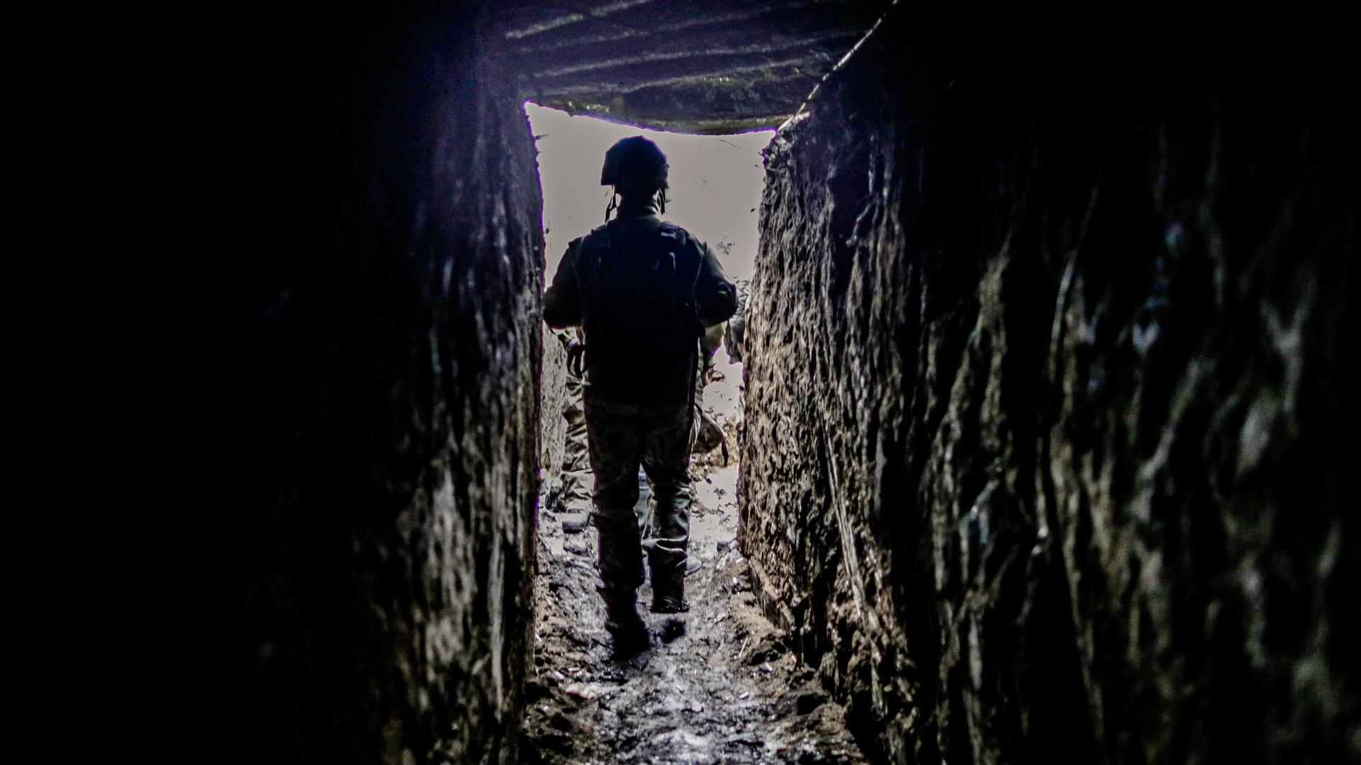 Ein ukrainischer Soldat geht durch einen Schützengraben.