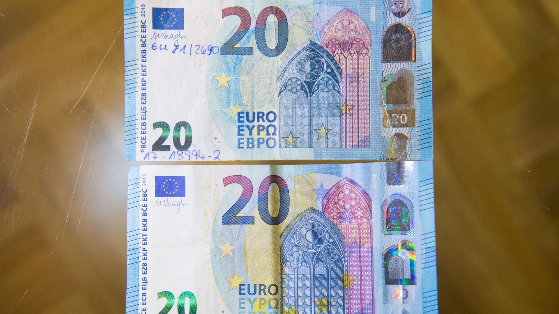 Ein gefälschter und sichergestellter 20-Euro-Schein (oben) und ein echter 20-Euro-Schein liegen zum Vergleich auf einem Tisch in der Deutschen Bundesbank. 