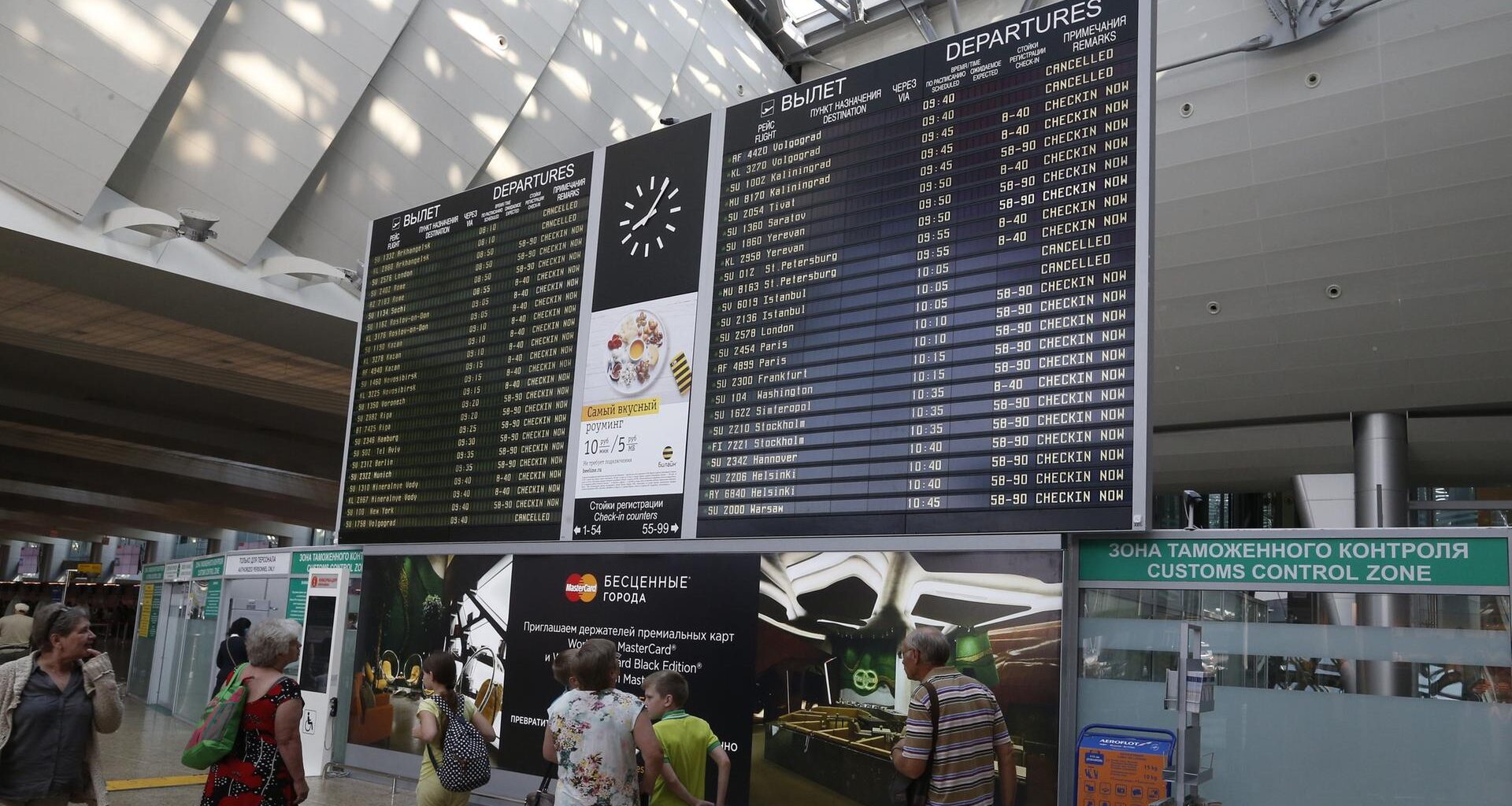 Menschen stehen an einer Informationstafel am Flughafen Scheremetjewo in Moskau.