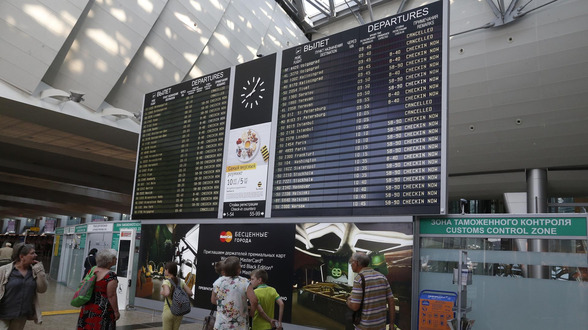 Menschen stehen an einer Informationstafel am Flughafen Scheremetjewo in Moskau.