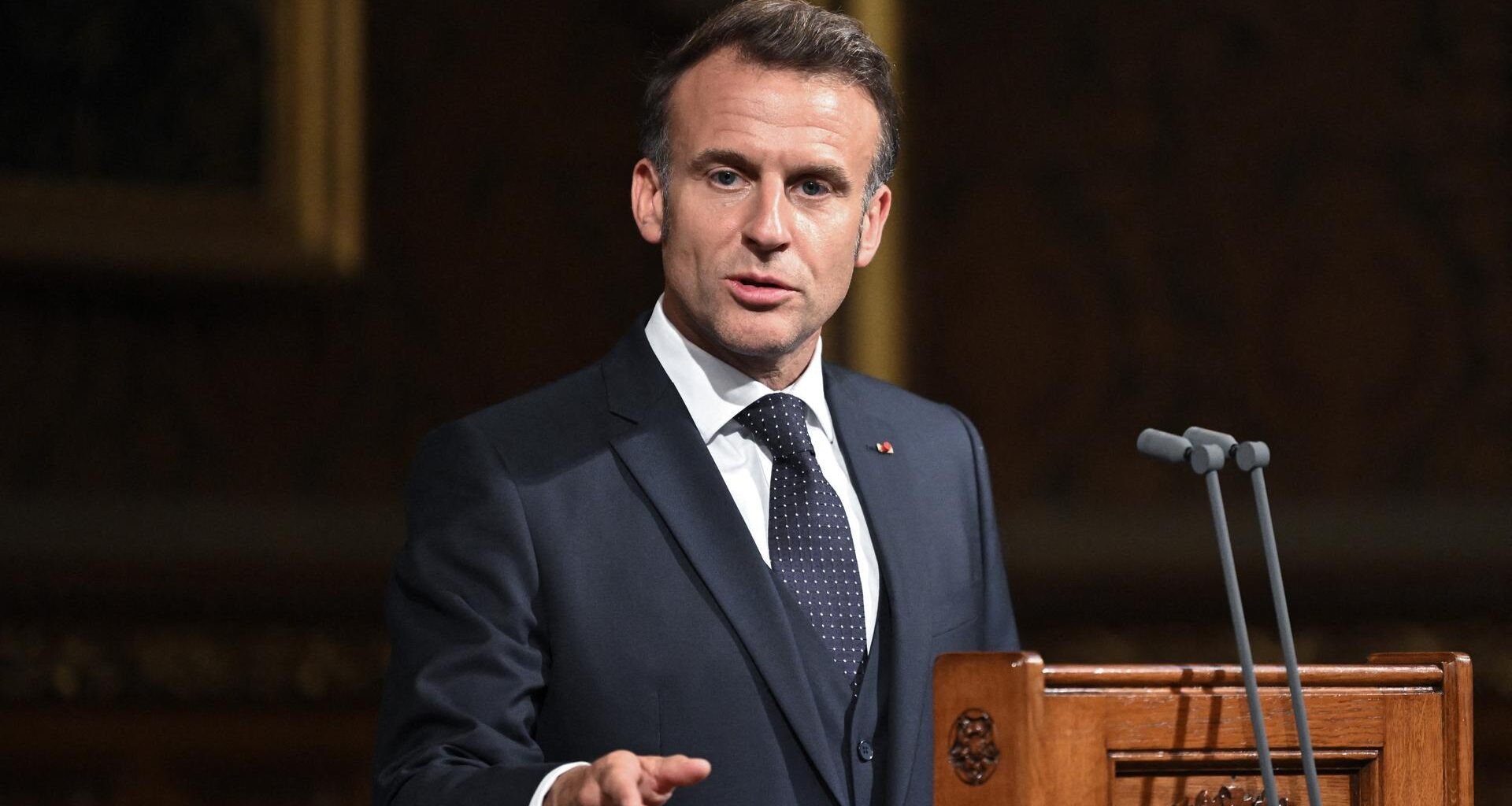 Frankreichs Präsident Macron steht vor dem Parlament in London hinter einem Rednerpult, er gestikuliert mit der rechten Hand.