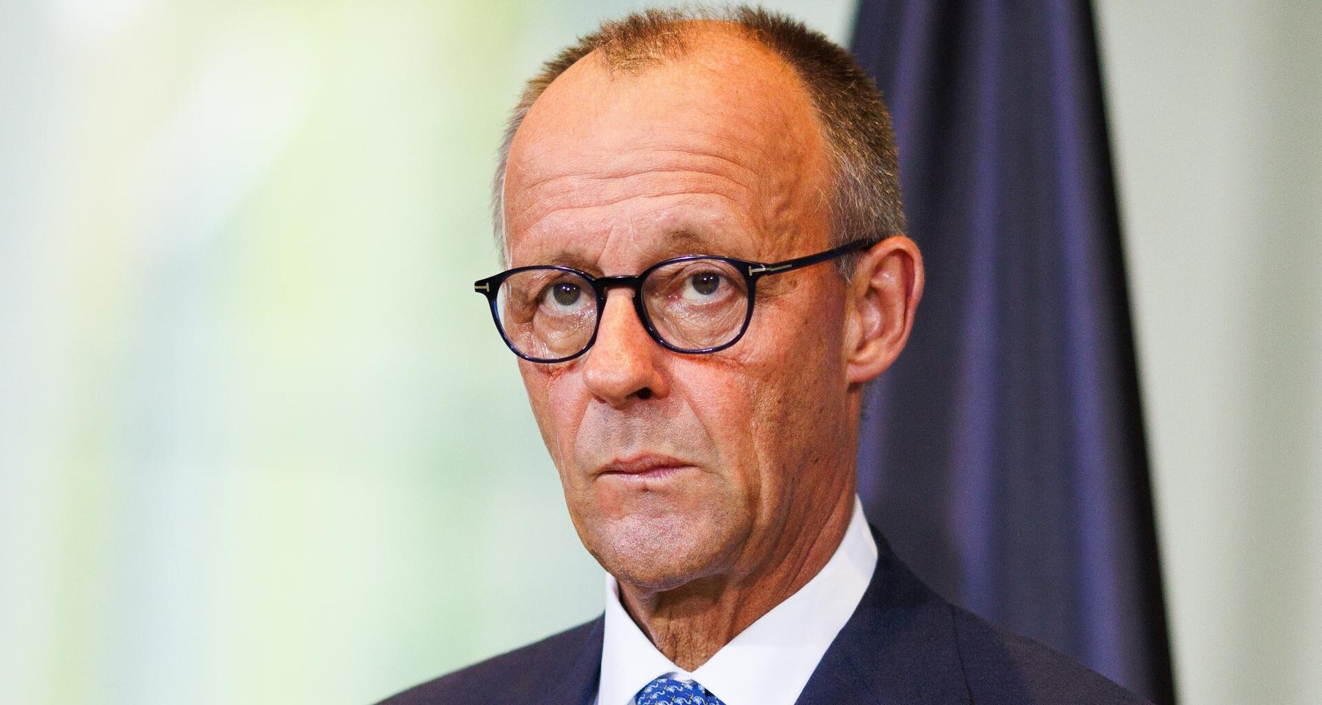 Bundeskanzler Friedrich Merz schaut in einem Raum ernst in die Kamera.