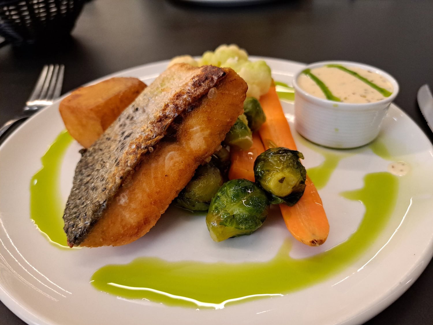 Wildlachs angerichtet mit Blumenkohl und Kartoffeln auf einem Teller