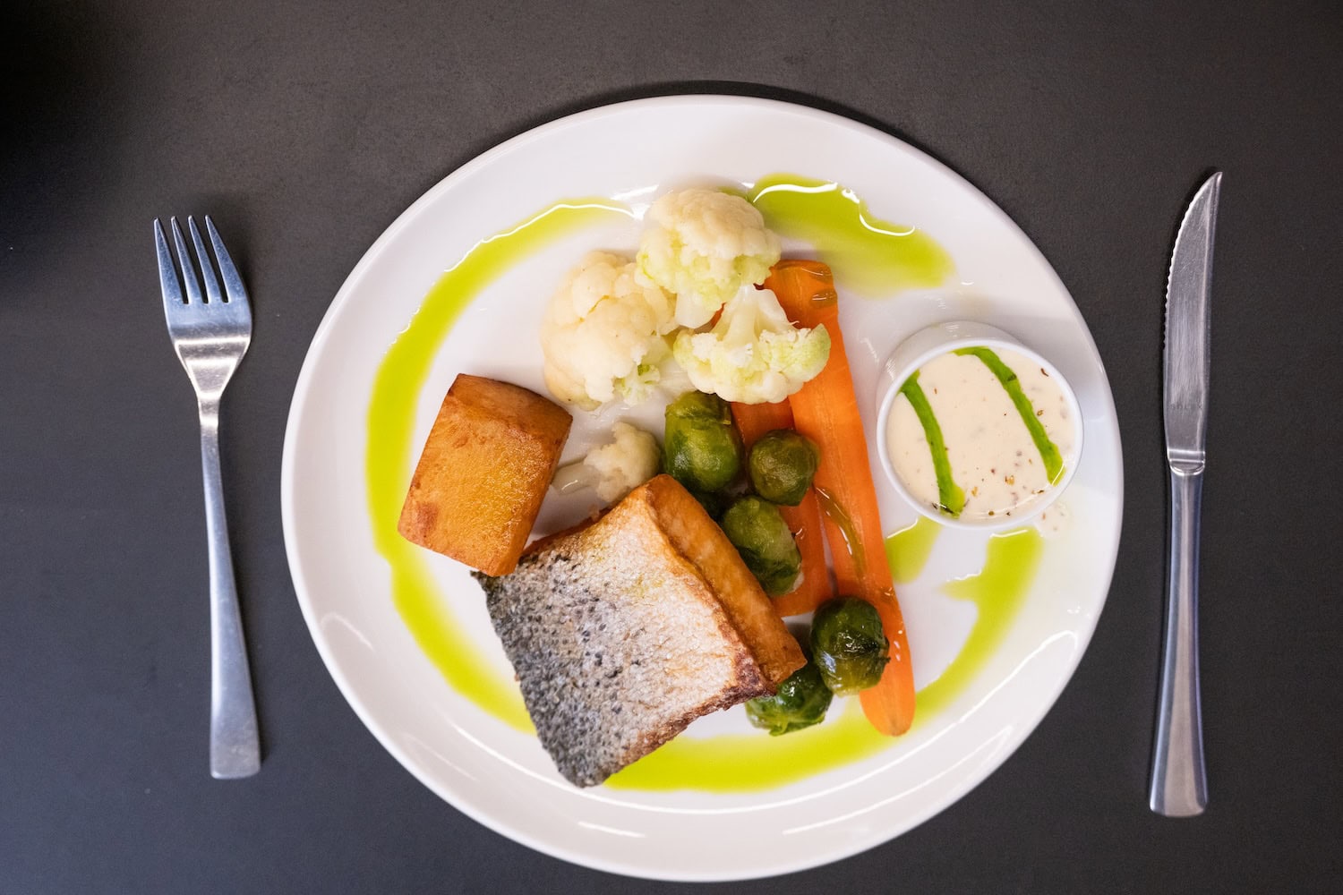 Wildlachs angerichtet mit Blumenkohl und Kartoffeln auf einem Teller