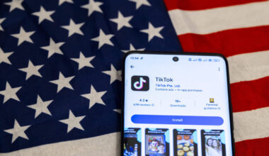 Smartphone liegt auf USA Fahne, TikTok wird im Appstore angezeigz