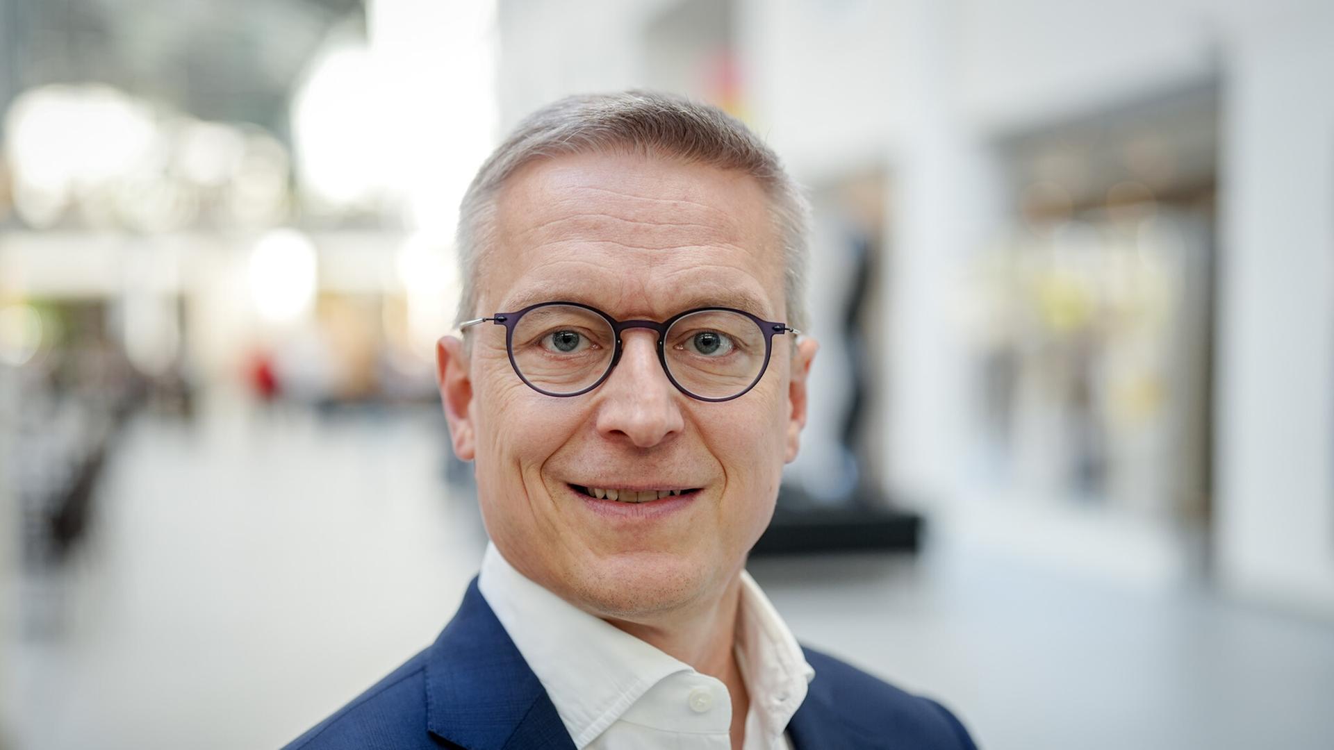 Porträt von Karsten Wildberger. Er blickt direkt in die Kamera.