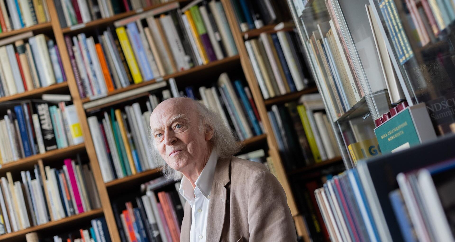 Antiquar Klaus Willbrand steht zwischen Büchern in seinem Antiquariat in Sülz.