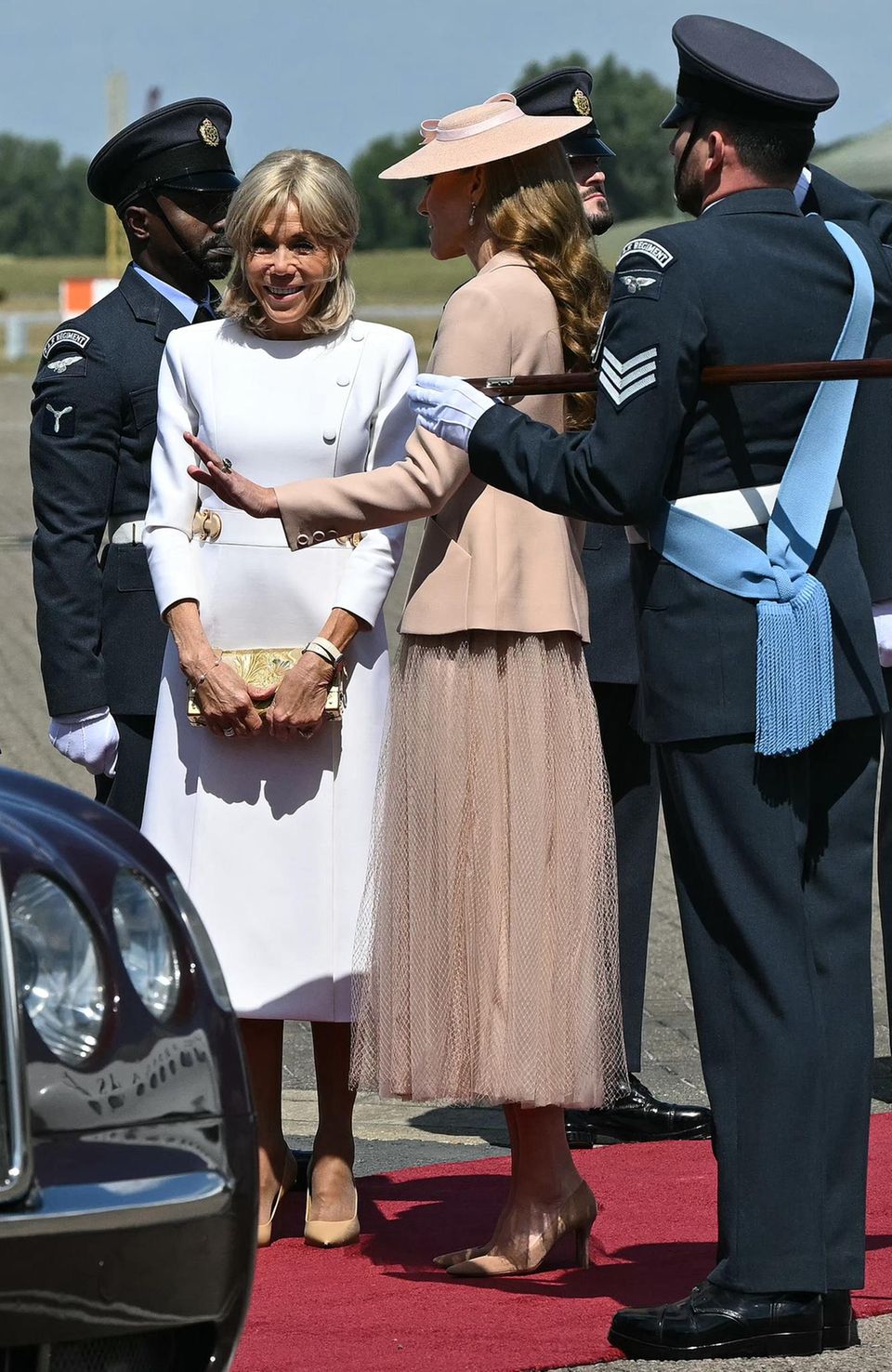 Brigitte Macron setzt auf ein weißes Kleid mit goldenen Details in Midi-Länge. 