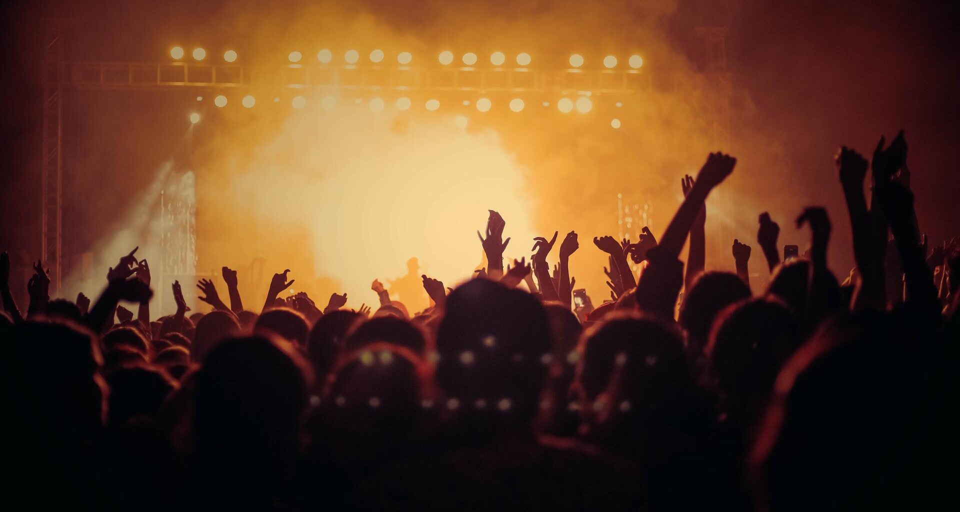 Bild einer Menschenmenge beim Konzert - das Publikum ist in gelbes Licht getaucht