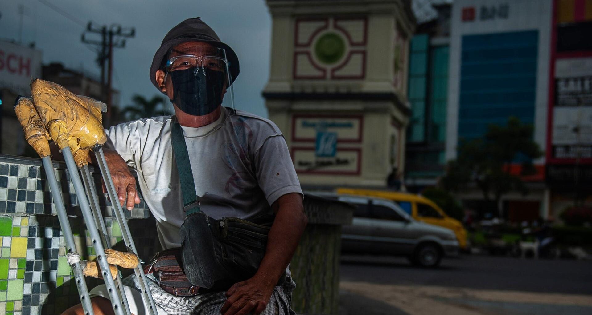 Ein Bewohner einer Leprakolonie sitzt mit einer Beinprothese an einer Kreuzung in Indonesien