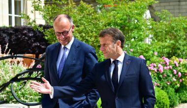 Friedrich Merz (links) und Emmanuel Macron (rechts) laufen gutgelaunt in dunklen Anzugen durch einen Park