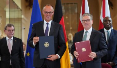 Bundeskanzler Friedrich Merz und Großbritanniens Premier Keir Starmer lächlen in die Kamera. In der Hand halten beide jeweils eine Mappe mit dem so eben unterzeichneten deutsch-britischen Freundschaftsvertrag.