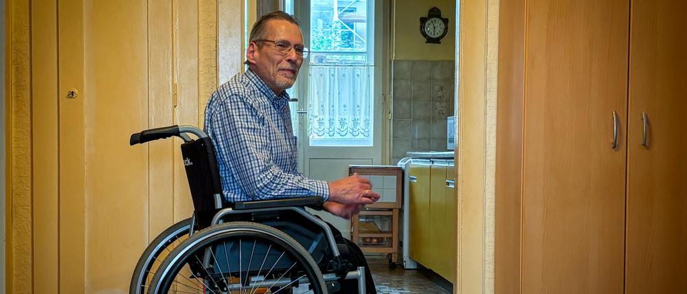 Michael Starke im Rollstuhl in der Diele seiner Mietwohnung, er trägt spezielle orthopädische Schuhe. 
