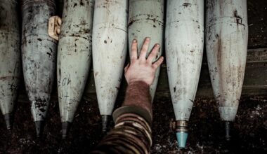 Artilleriegranaten und die Hand eines Soldaten.