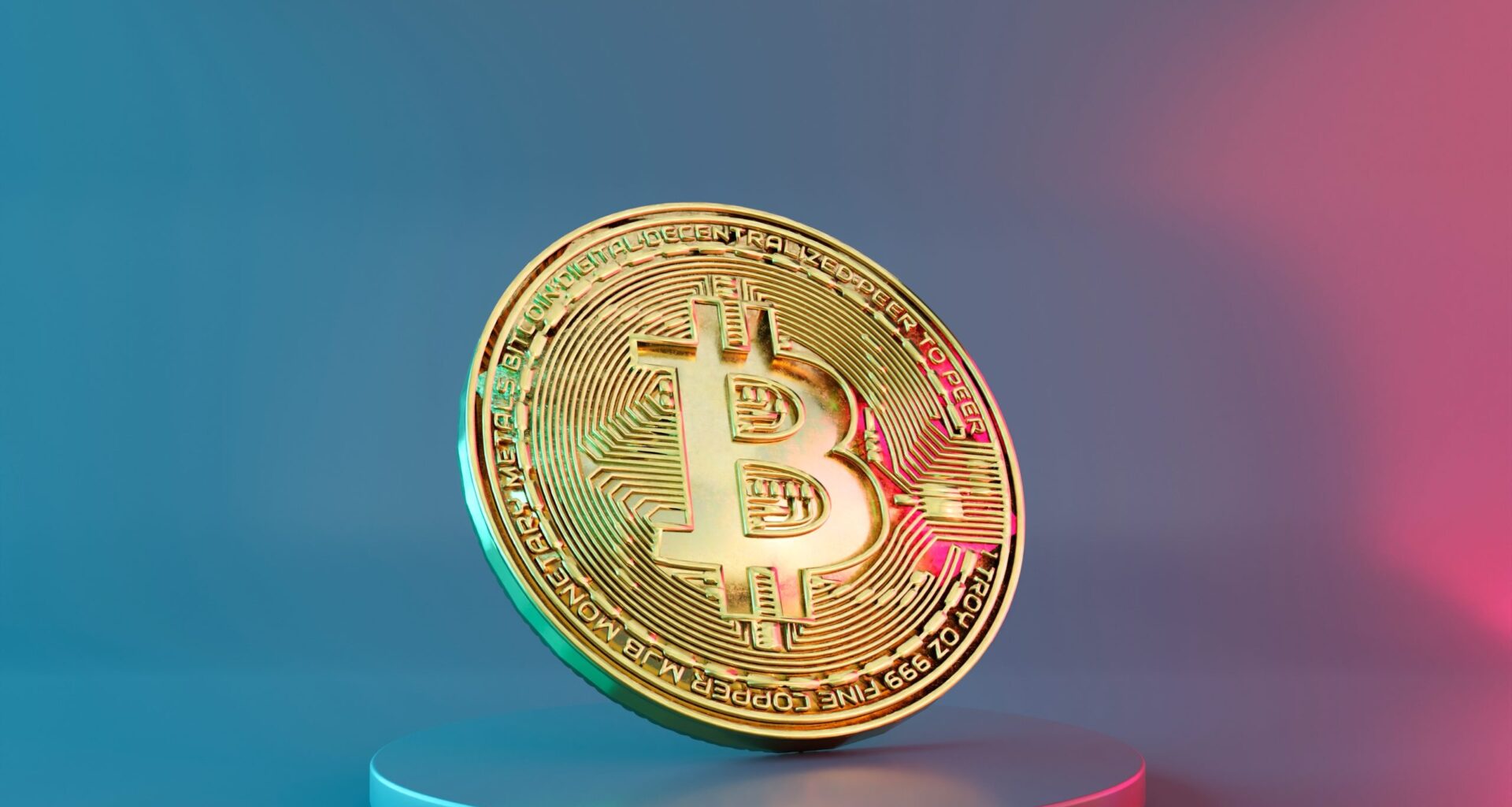 Eine goldene Bitcoin-Münze steht aufrecht auf einem runden Podest, ihre glänzende Oberfläche fängt das Licht vor einem Hintergrund mit blauem und rosa Farbverlauf ein.