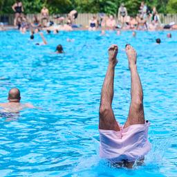 Kinder und Erwachsene tummeln sich am 09.07.2024 bei hochsommerlichen Temperaturen im Prinzenbad, während ein Mann ins Becken springt. (Quelle: Picture Alliance/Annette Riedl)