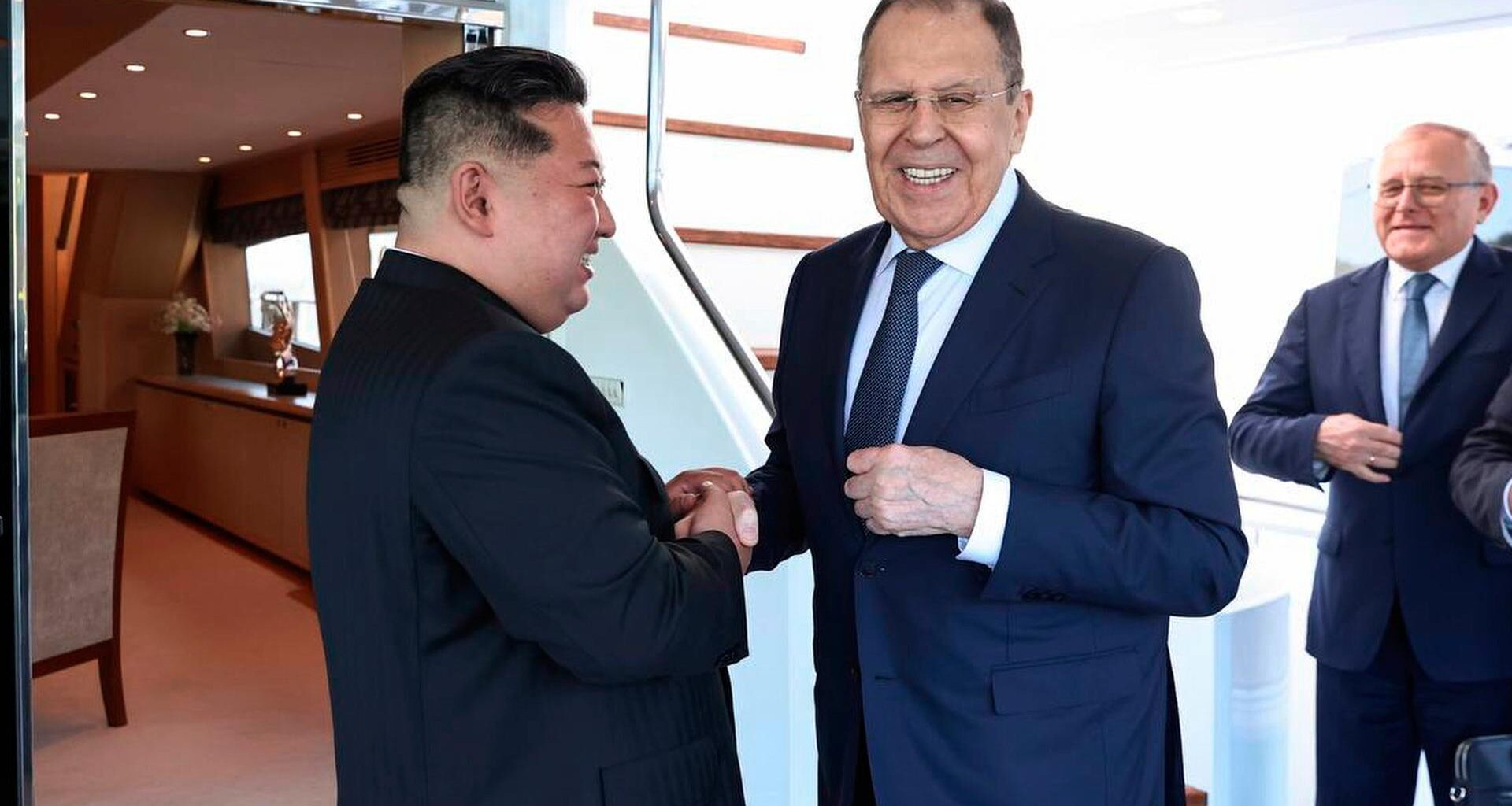 Kim hält mit beiden Händen die rechte Hand von Lawrow und lächelt ihn an, Lawrow blickt derweil in Richtung Kamera und lächelt.