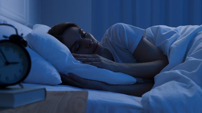 Eine junge Frau schläft im dunklen Schlafzimmer.
