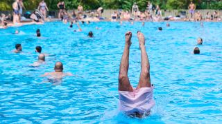 Kinder und Erwachsene tummeln sich am 09.07.2024 bei hochsommerlichen Temperaturen im Prinzenbad, während ein Mann ins Becken springt. (Quelle: Picture Alliance/Annette Riedl)