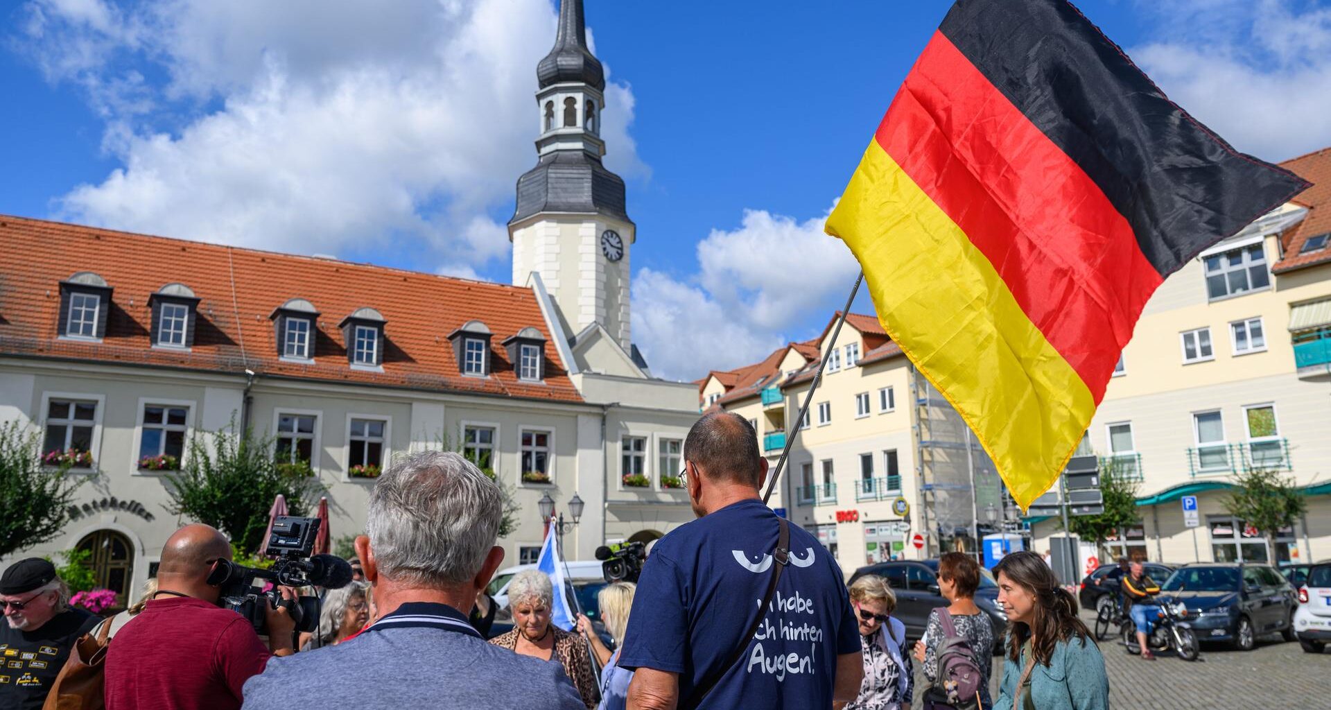 Einige Teilnehmer einer Protestveranstaltung gegen die Bürgermeisterin der Stadt Spremberg im Landkreis Spree-Neiße haben sich auf dem Marktplatz versammelt.