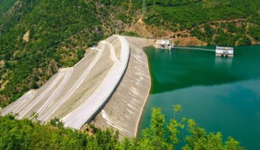 Der Fierza-Stausee ist mit seiner Fläche von 72,6 Quadratkilometern der größte Stausee in Albanien. Grünblaues Wasser wird von einer Staumauer gehalten, die weit in die Tiefe ragt.