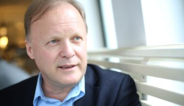 Stephan Werhahn sitzt auf einer Bank in einem Café und schaut aus dem Fenster. Er trägt ein hellblaues Hemd zum dunkelblauen Anzug.