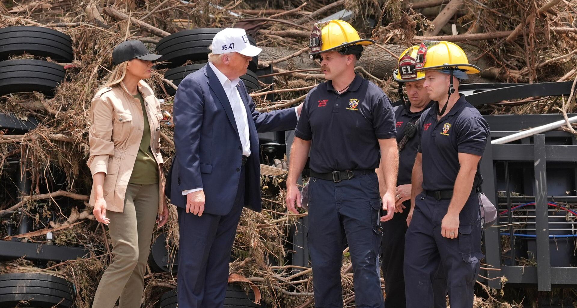 Trump und seine Frau unterhalten sich mit Rettungskräften. Sie stehen nebeneinander.