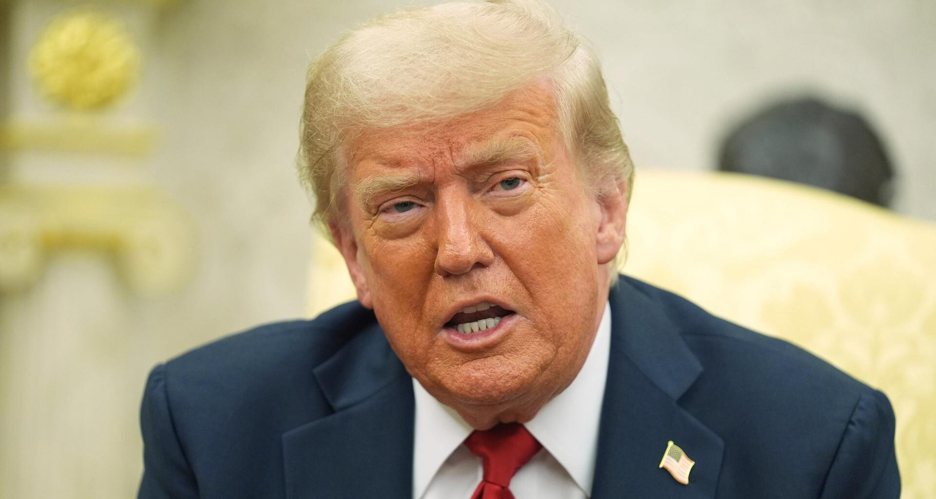 US-Präsident Donald Trump sitzt auf einem Stuhl und spricht.