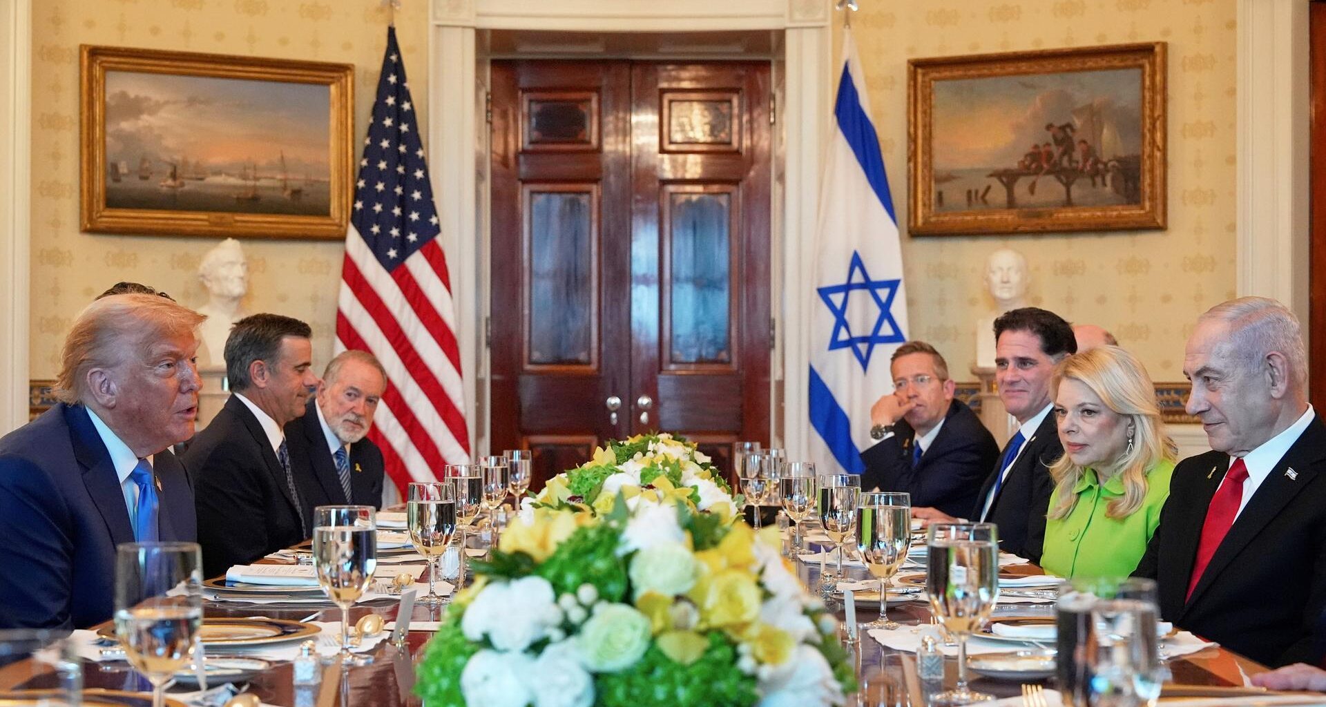 Donald Trump und Benjamin Netanjahu sitzen zusammen mit anderen Personen an einem festlich gedeckten Tisch im Weißen Haus.