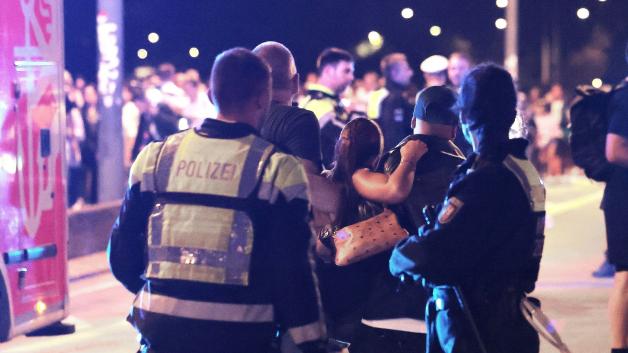 Ersthelfer und Polizisten tragen eine Verletze zu den Sanitätern auf einer Brücke.
